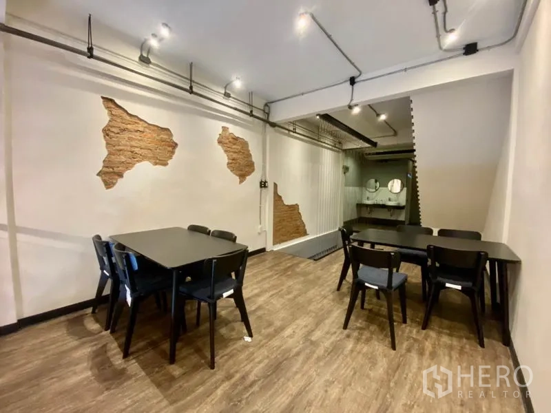 Shophouse for rent in Pathum Wan, Bangkok - Rear dining or meeting room with industrial lighting, white walls with brick accents and wash area at back.