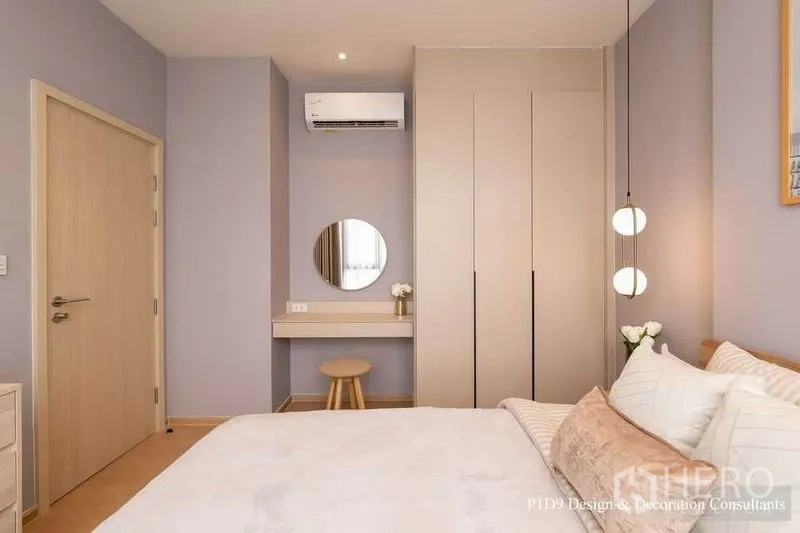 Condominium for rent in Watthana, Bangkok - Calm bedroom with built‑in wardrobe, dressing nook with round mirror, pendant lights and air conditioning.