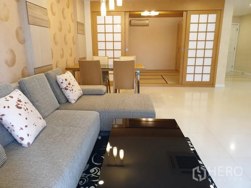 คอนโด ให้เช่าในWatthana, Bangkok - ห้องนั่งเล่นพร้อมโซฟาตัวแอล โต๊ะกลางสีดำ ชุดโต๊ะอาหาร และประตูบานเลื่อนสไตล์โชจิ