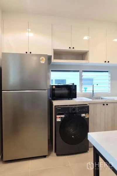 Detached House for rent in Bang Phli, Samut Prakan - Modern kitchen with glossy cabinets, large fridge, washer and microwave by window.