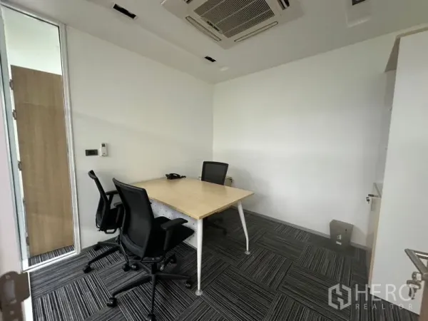Office Space for rent - Compact meeting room with two chairs, white walls, and built-in air-conditioning.