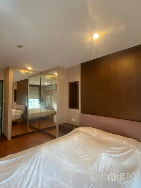 公寓 出租或出售在Watthana, Bangkok - 卧室含深色木质床头、镜面衣柜与暖色筒灯