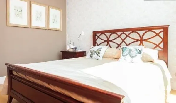 Condominium for rent or sale in Khlong Toei, Bangkok - Bright guest bedroom with wooden bedframe, neutral walls, and framed art.