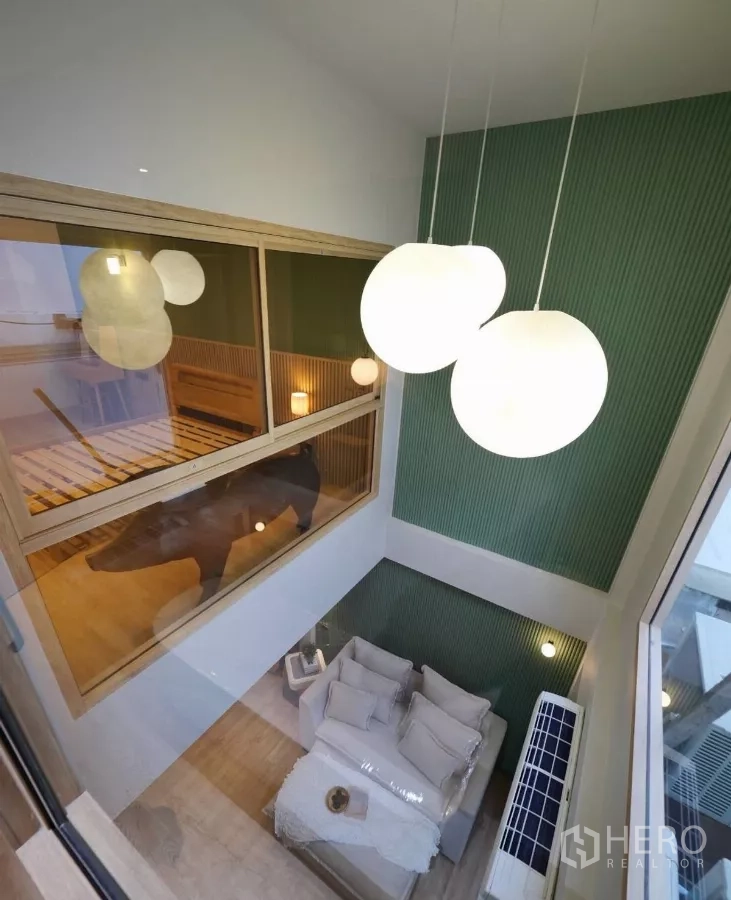 ทาวน์เฮาส์ ให้เช่าในWatthana, Bangkok - มุมมองจากชั้นลอยลงสู่ห้องนั่งเล่น เห็นโคมไฟทรงกลมและผนังสีเขียว
