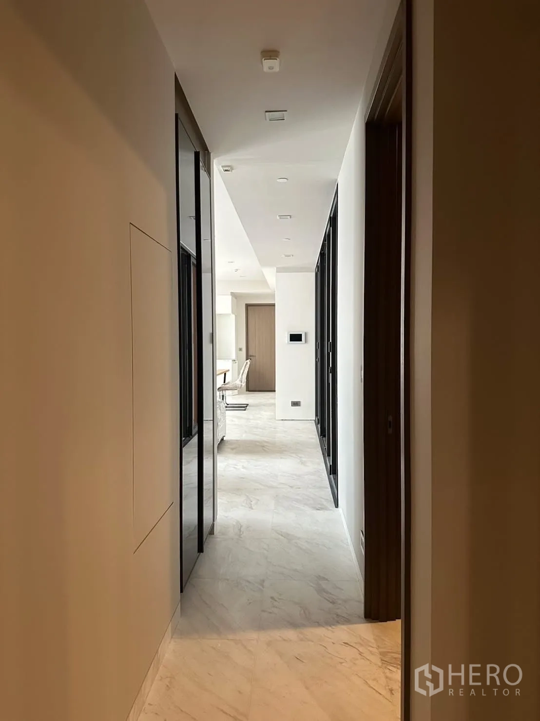 Condominium for rent or sale in Watthana, Bangkok - Long corridor with recessed lighting and marble floors.