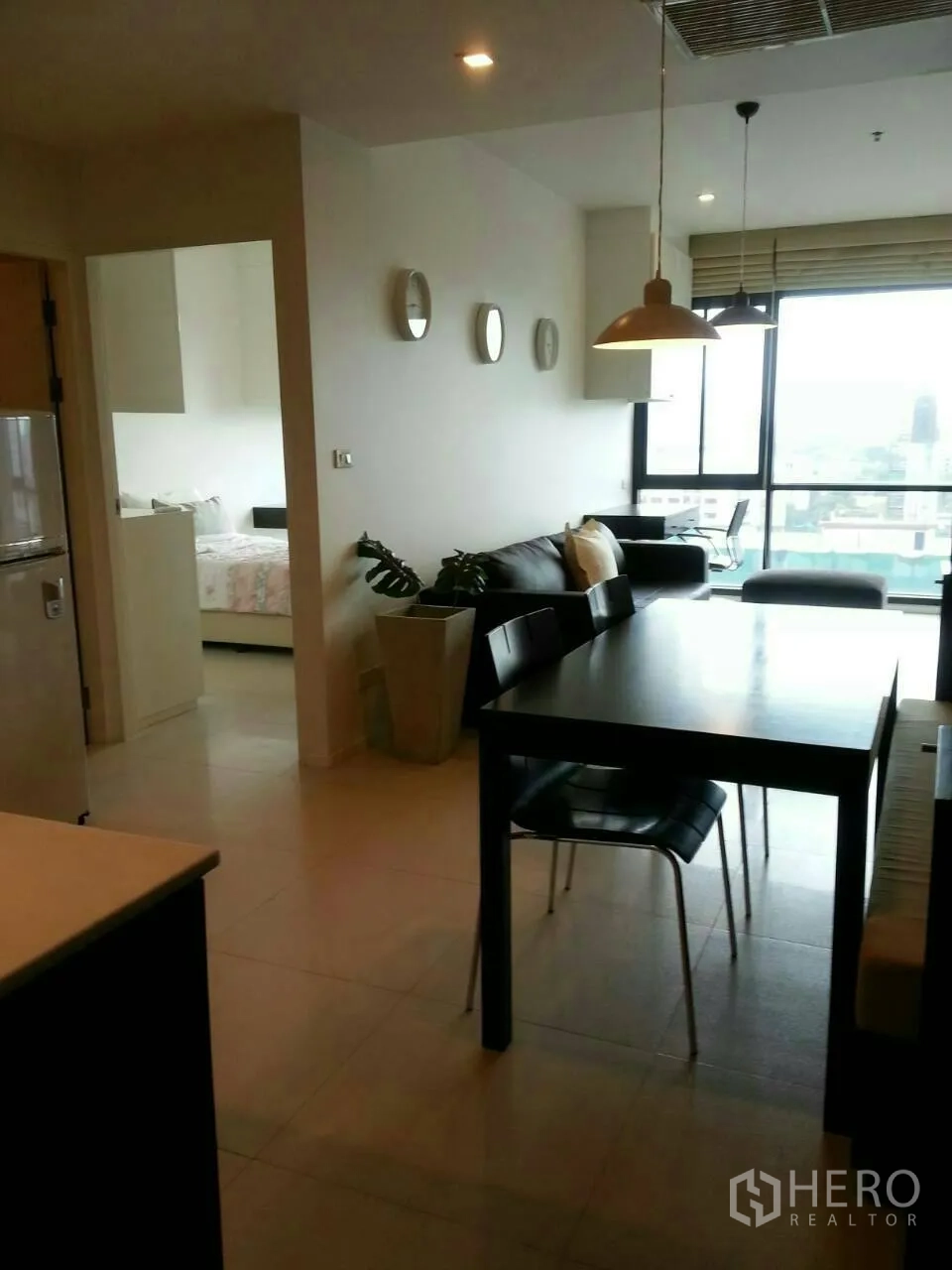 คอนโด ให้เช่าในPhaya Thai, Bangkok - โต๊ะทานอาหารพร้อมไฟแขวน มองไปยังห้องนั่งเล่นและหน้าต่างสูงเต็มบานวิวเมือง