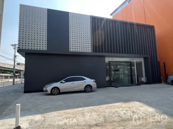 展厅 出租在Khan Na Yao, Bangkok - 展示厅正立面，玻璃入口、竖向格栅以及宽敞的前场停车区。