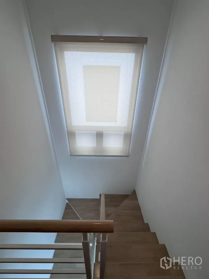 Detached House for rent in Samut Prakan - Stairwell with a large window and roller blind letting in natural light.