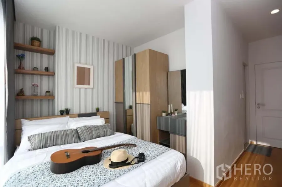 Condominium for sale in Bang Rak, Bangkok - Bright bedroom with striped feature wall, built-in shelves and wardrobe.