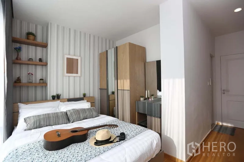 Condominium for sale in Bang Rak, Bangkok - Bright bedroom with striped feature wall, built-in shelves and wardrobe.