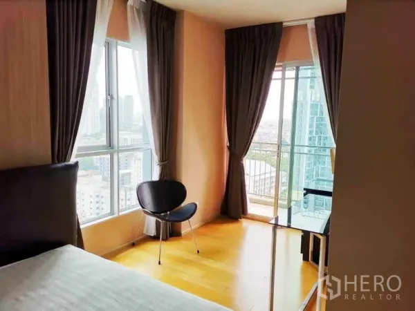 Condominium for sale in Khlong San, Bangkok - Corner bedroom with floor-to-ceiling windows, balcony door and city view in a Khlong San condo.