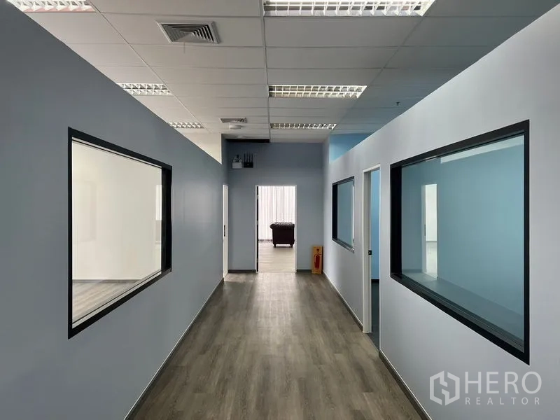 办公空间 出租 - 走廊两侧玻璃隔断房间，木质地板与明亮日光灯。