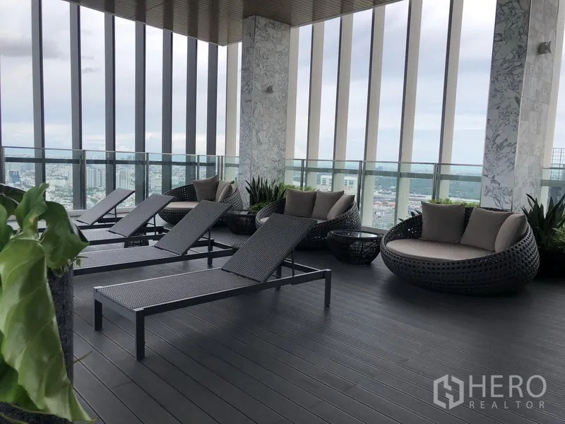 Condominium for rent in Khlong Toei, Bangkok - Sky lounge terrace with sun loungers and round daybeds overlooking Bangkok.
