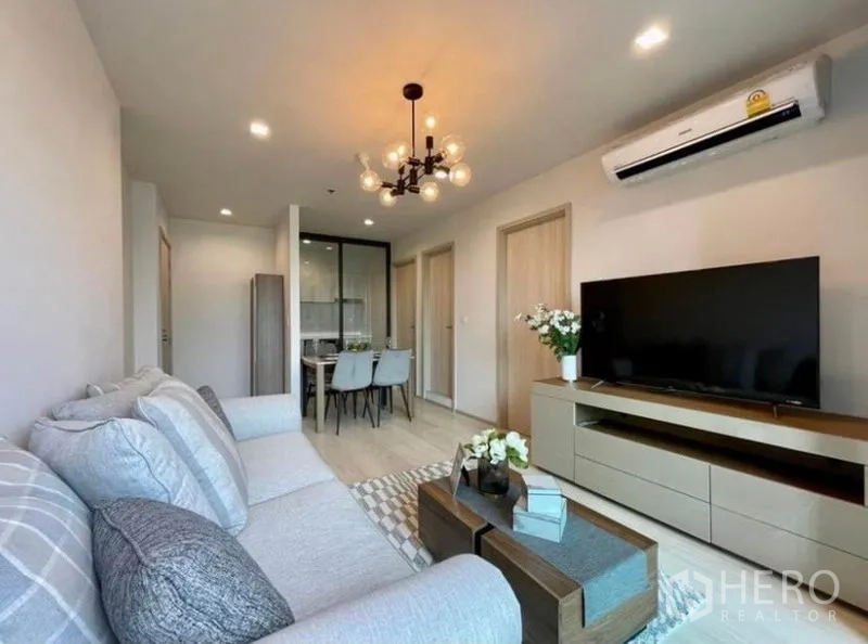 Condominium for rent in Pathum Wan, Bangkok - Lounge with media unit, hallway to bedrooms, and a glass partition beside the dining nook.
