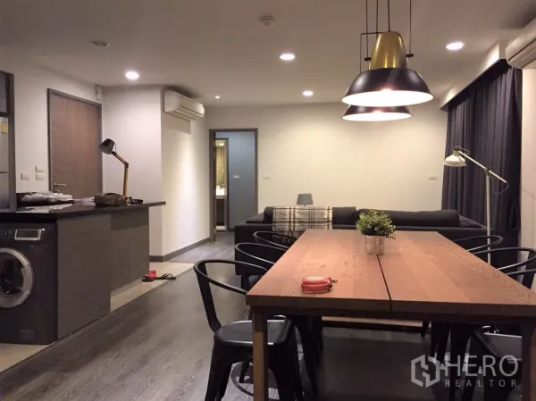 คอนโด ให้เช่าหรือขายในWatthana, Bangkok - โซนรับแขกแบบเปิดโล่ง พื้นไม้ โต๊ะทานข้าว โคมไฟแขวน เคาน์เตอร์ครัวพร้อมเครื่องซักผ้า และโซฟาเชื่อมสู่ห้องนอน