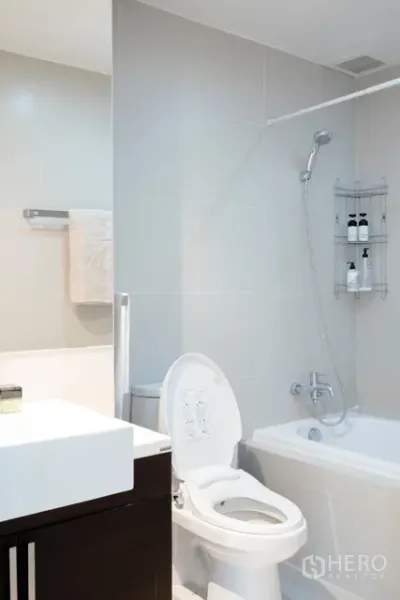 公寓 出租在Khlong Toei, Bangkok - 现代浴室，带浴缸与淋浴、白色瓷砖与洗手台。