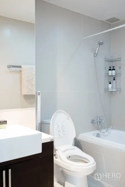 公寓 出租在Khlong Toei, Bangkok - 现代浴室，带浴缸与淋浴、白色瓷砖与洗手台。