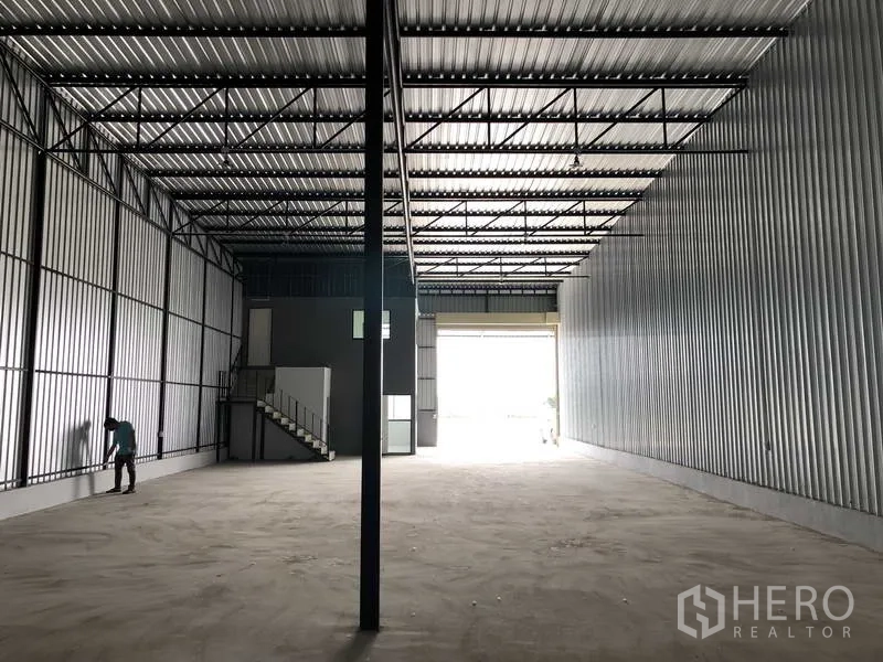 คลังสินค้า ให้เช่าในKhlong Luang, Pathum Thani - มุมมองภายในโกดังลึก หลังคาสูงมีแสงสว่าง บันไดขึ้นออฟฟิศ และประตูม้วน