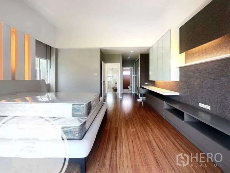 Townhouse for rent in Saphan Sung, Bangkok - Spacious bedroom with wood flooring, long built-in workspace and ensuite access.