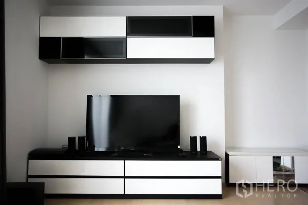 Condominium for rent in Watthana, Bangkok - Modern living room media wall with black-and-white cabinets and a flat-screen TV.