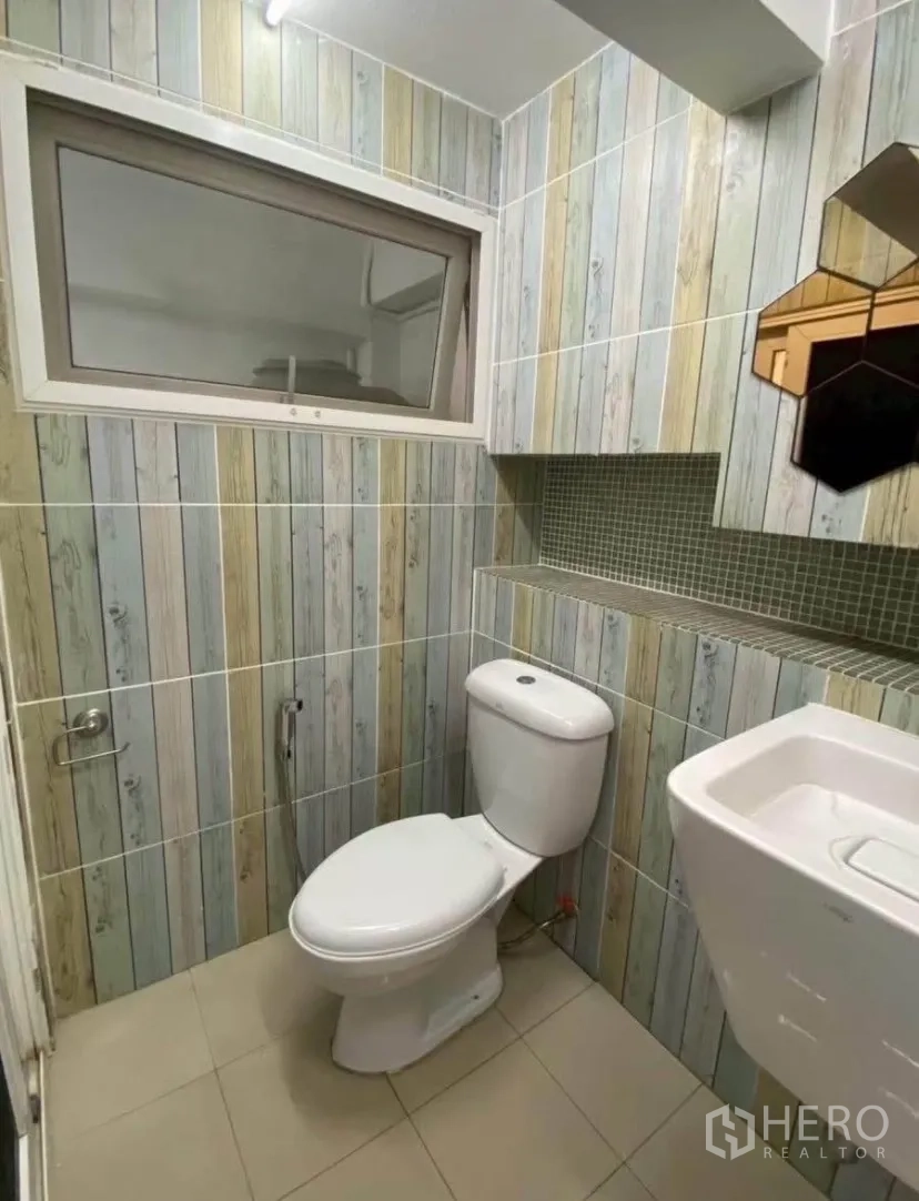 联排别墅 for rent in Phra Khanong, Bangkok - 小巧卫浴，木纹竖纹墙砖，带窗户、坐便和壁挂洗手盆。