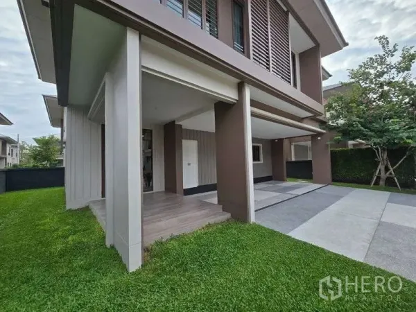 独立式住宅 出租在Bang Kapi, Bangkok - 房屋侧面，绿草坪、前门廊与宽敞车道。