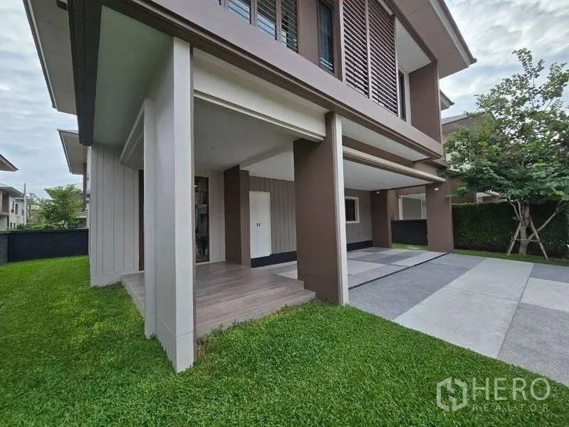 独立式住宅 出租在Bang Kapi, Bangkok - 房屋侧面，绿草坪、前门廊与宽敞车道。