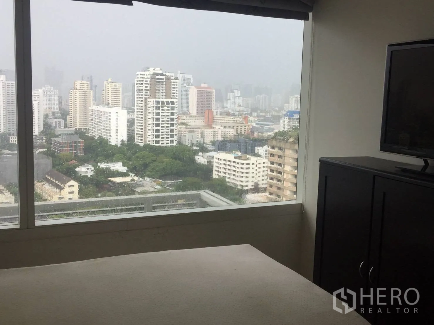 Condominium for rent in Watthana, Bangkok - Bedroom with large picture window offering city view and TV cabinet.