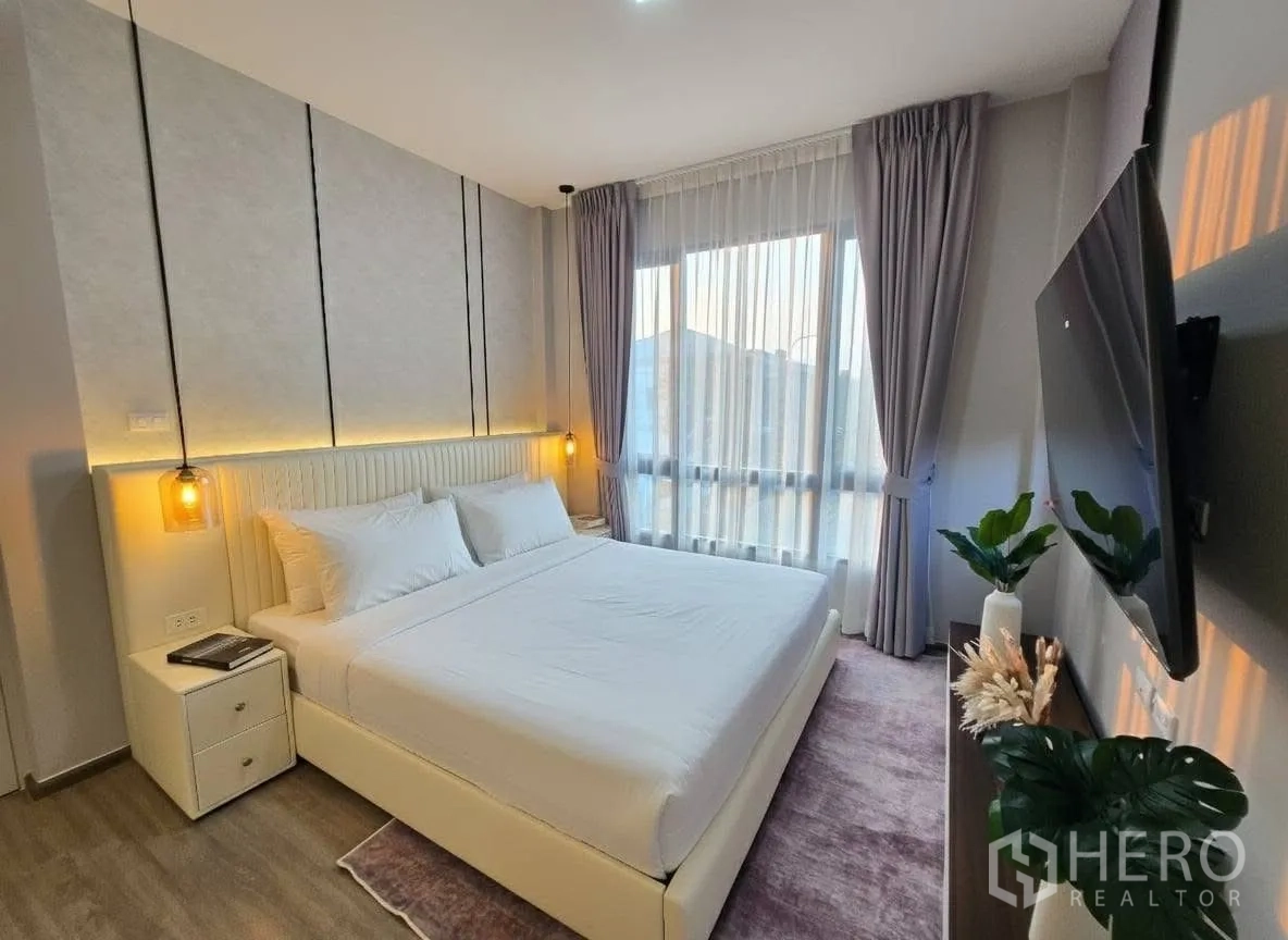 Detached House for rent or sale in Bang Phli, Samut Prakan - Master bedroom angle with king bed, large TV wall, and sheer curtains bringing in daylight.