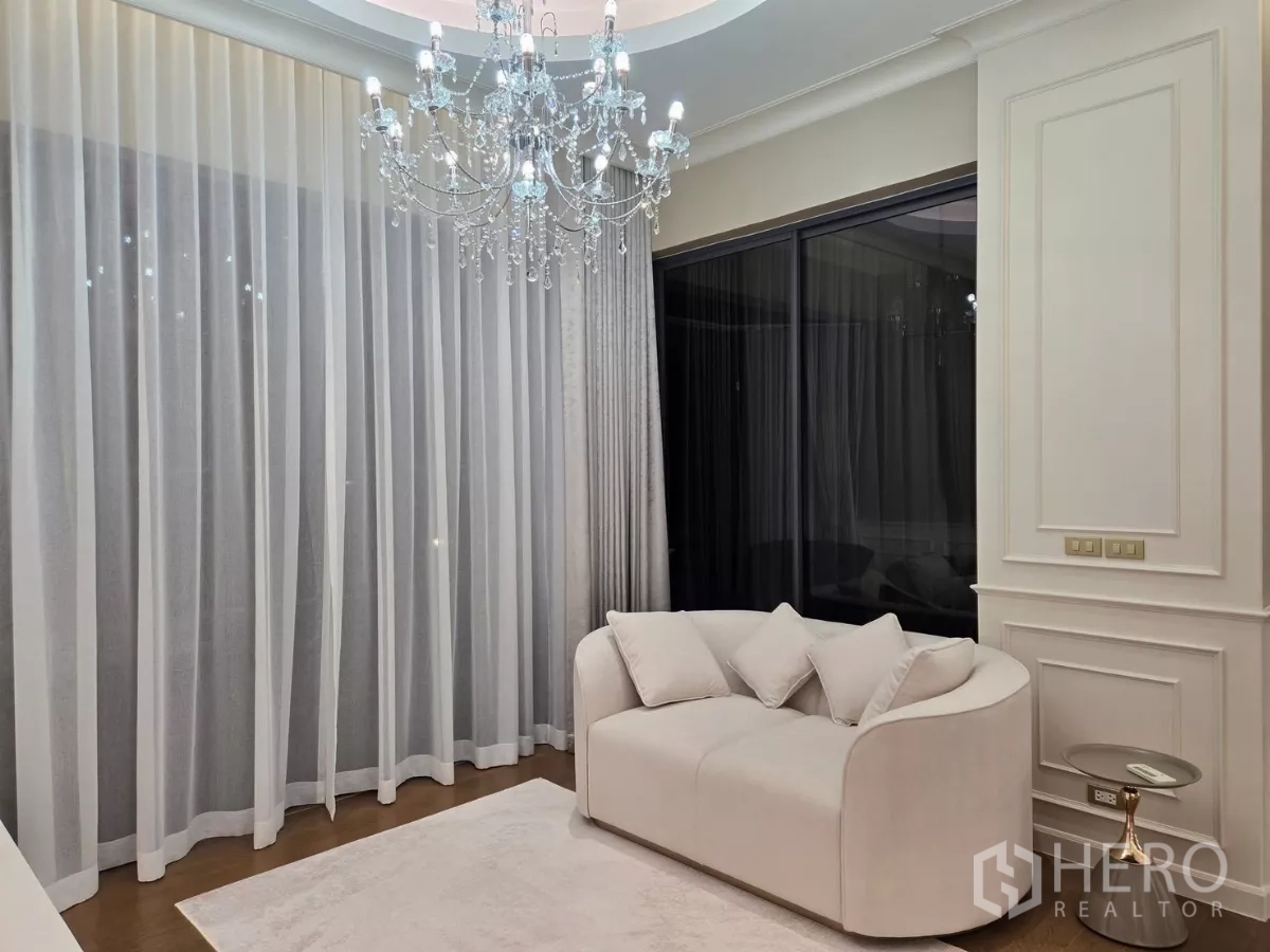 Detached House for rent or sale in Bang Kapi, Bangkok - Bright lounge corner with white sofa, crystal chandelier and sheer floor-to-ceiling curtains.