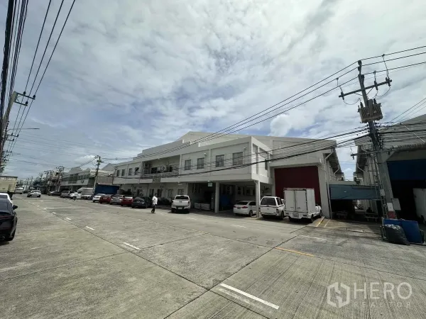 工厂 出租在Khlong Luang, Pathum Thani - 工业园区内白色厂房外观，宽阔混凝土道路与装卸区。