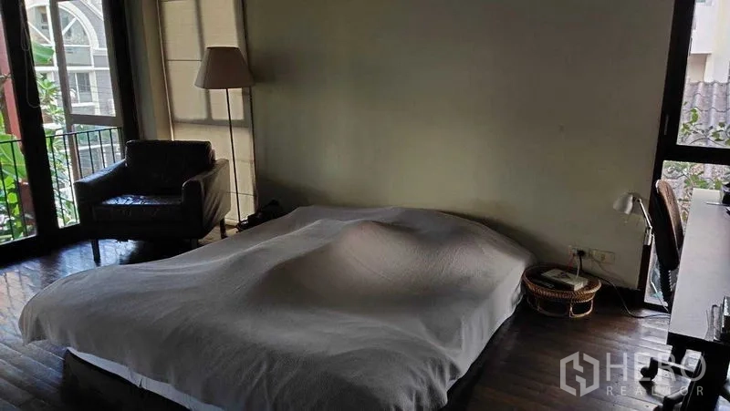 Detached House for sale in Suan Luang, Bangkok - Master bedroom with large windows, armchair and wood floors for natural light.