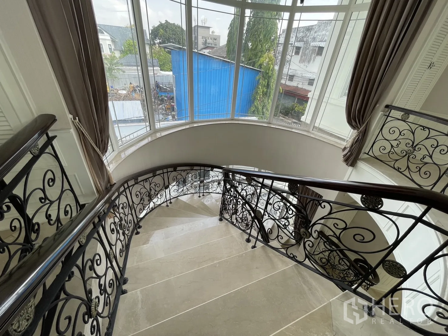 独立式住宅 出租在Chatuchak, Bangkok - 弧形楼梯旁落地窗与窗帘，自然采光充足