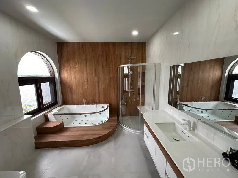 Detached House for sale in Sai Noi, Nonthaburi - Luxury bathroom with jacuzzi tub on wood platform, glass shower and large vanity.