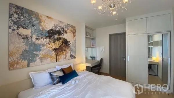 Condominium for rent or sale in Watthana, Bangkok - Serene bedroom with chandelier, large wall art, work desk and built-in wardrobe.