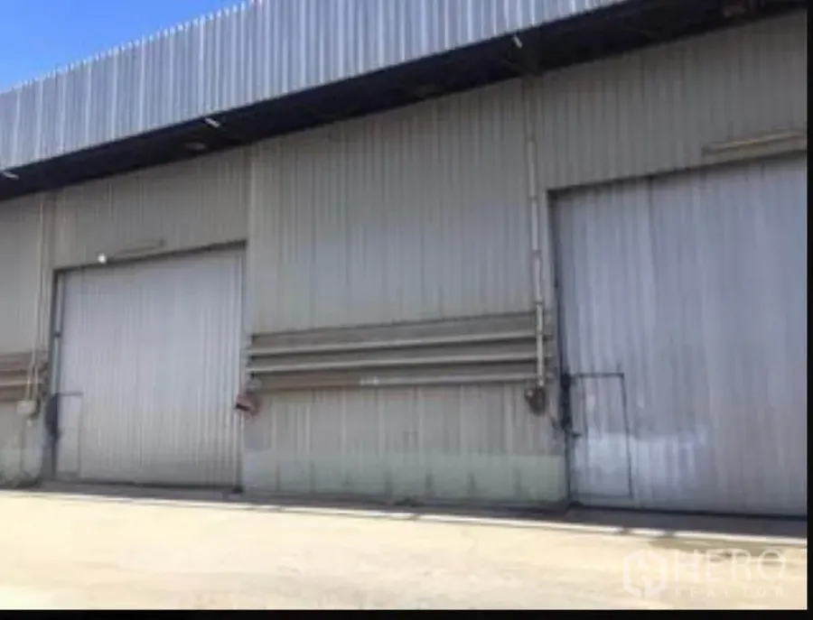 คลังสินค้า ให้เช่าในSai Mai, Bangkok - ด้านหน้าคลังสินค้าที่กรุด้วยเมทัลชีท ประตูบานเลื่อนขนาดใหญ่ และลานคอนกรีตกลางแจ้ง