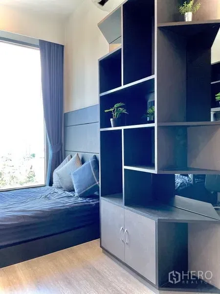 公寓 出租在Bang Na, Bangkok - 卧室一角，靠窗榻榻米与深色开放格架，配落地窗帘。