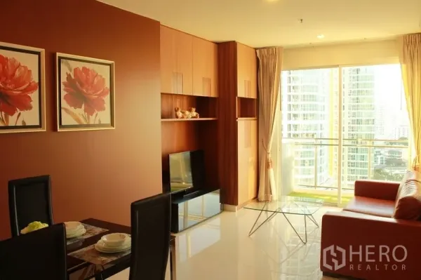 公寓 出租在Watthana, Bangkok - 开放式客厅，内置收纳与餐桌，阳台可观周边高楼景致。