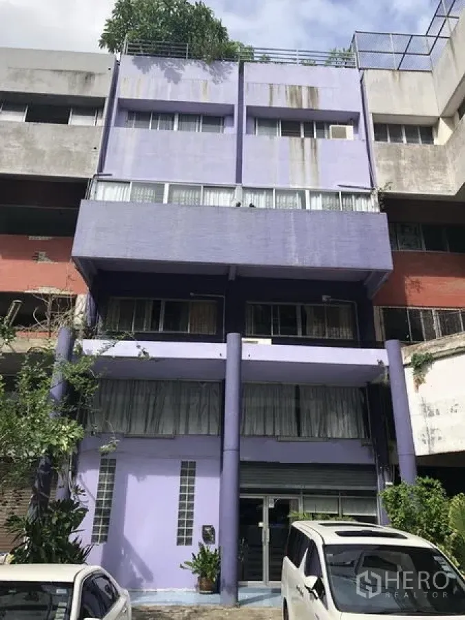 Shophouse for sale in Khlong Toei, Bangkok - Four-storey purple shophouse exterior with front parking area.