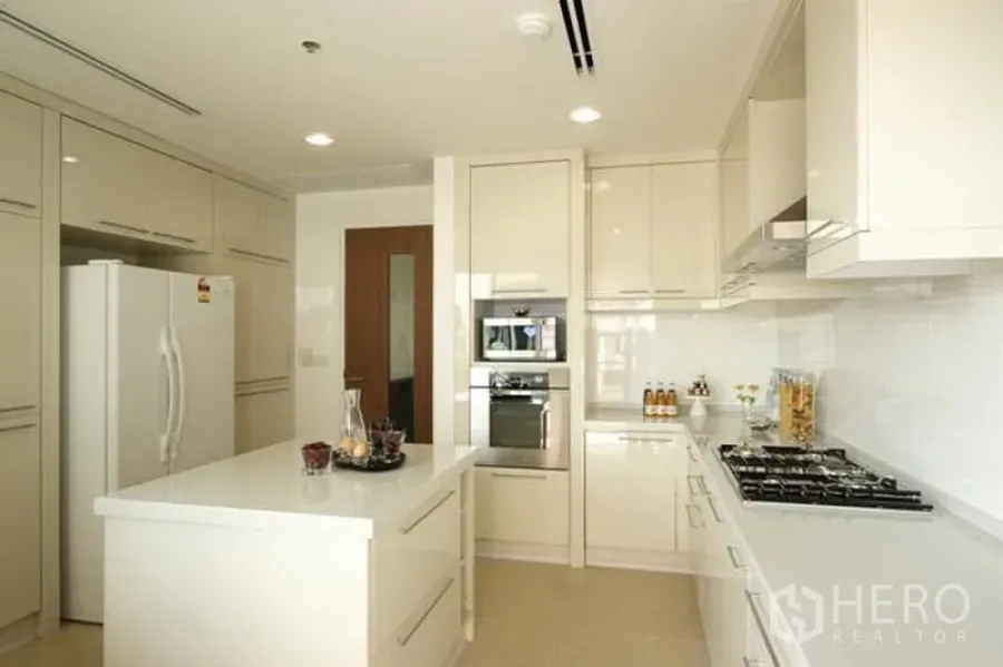 Condominium for rent in Watthana, Bangkok - Bright modern kitchen with white cabinetry, island counter, gas hob and built-in oven in a Bangkok condominium.
