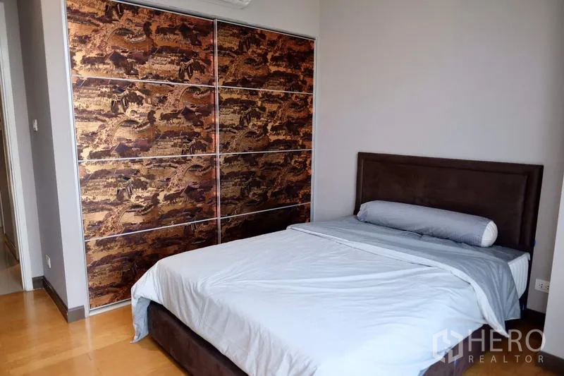 Condominium for rent in Watthana, Bangkok - Bedroom with upholstered bed and built-in wardrobe featuring patterned panels.