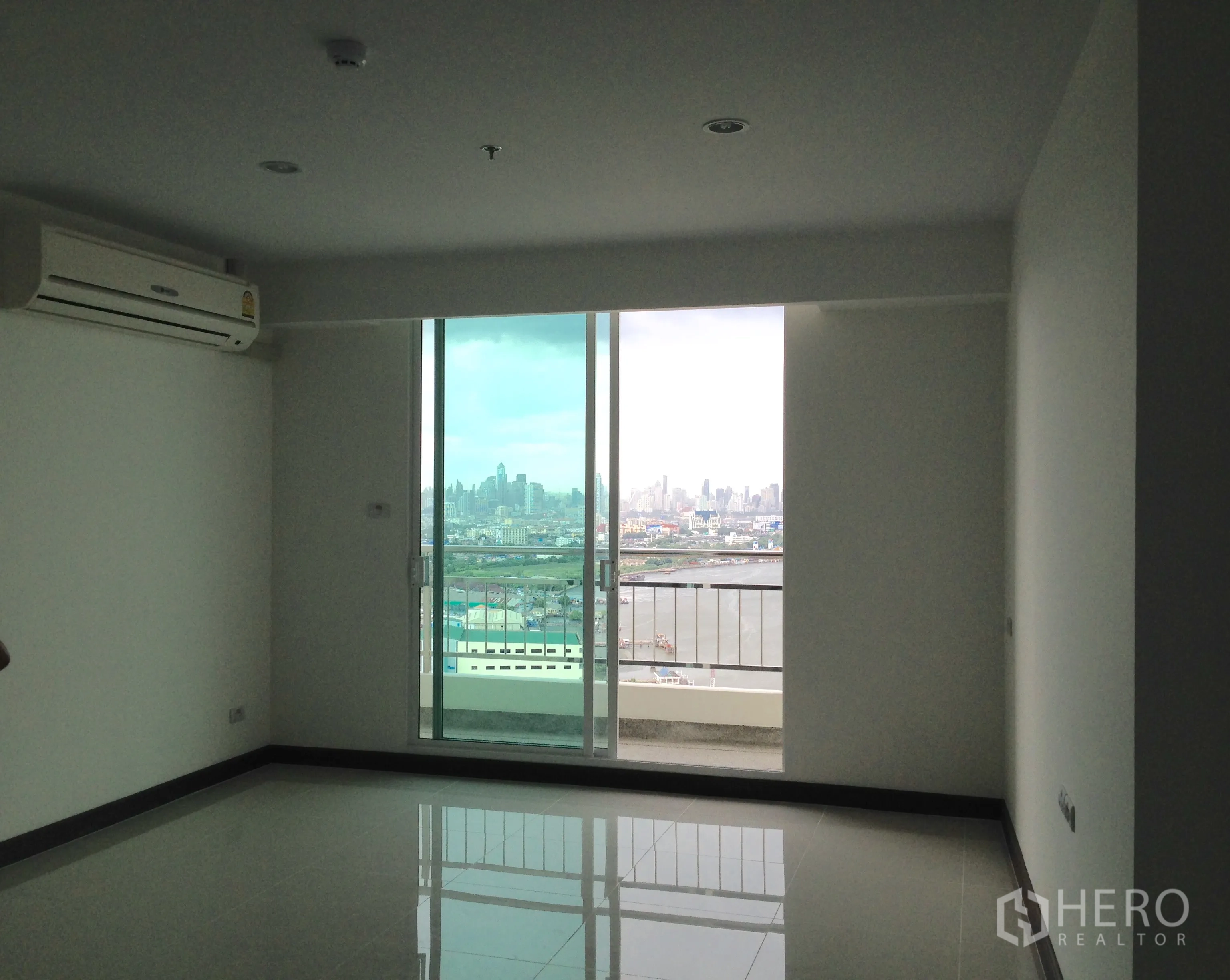 公寓 for sale in Yan Nawa, Bangkok - 明亮客厅，亮面地砖，墙式空调，落地推拉门通向观景阳台。