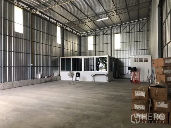 Warehouse for rent in Wang Thonglang, Bangkok - Open warehouse interior with high roof, concrete floor, and an internal office block.