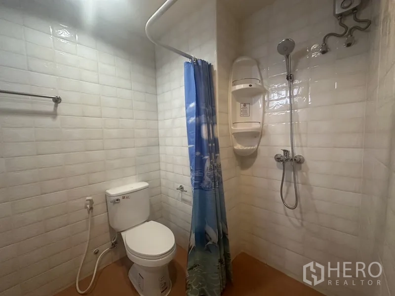 คอนโด ขายในWatthana, Bangkok - ห้องน้ำปูกระเบื้องสีขาว ฝักบัว โถสุขภัณฑ์ และผ้าม่านสีน้ำเงิน