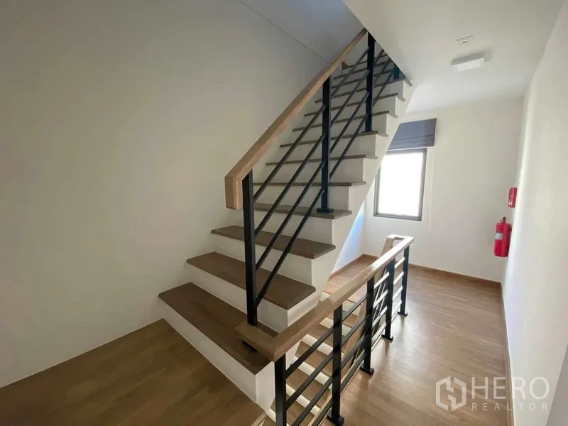 联排别墅 出租在Prawet, Bangkok - 楼上楼梯，木踏步与黑色金属栏杆。