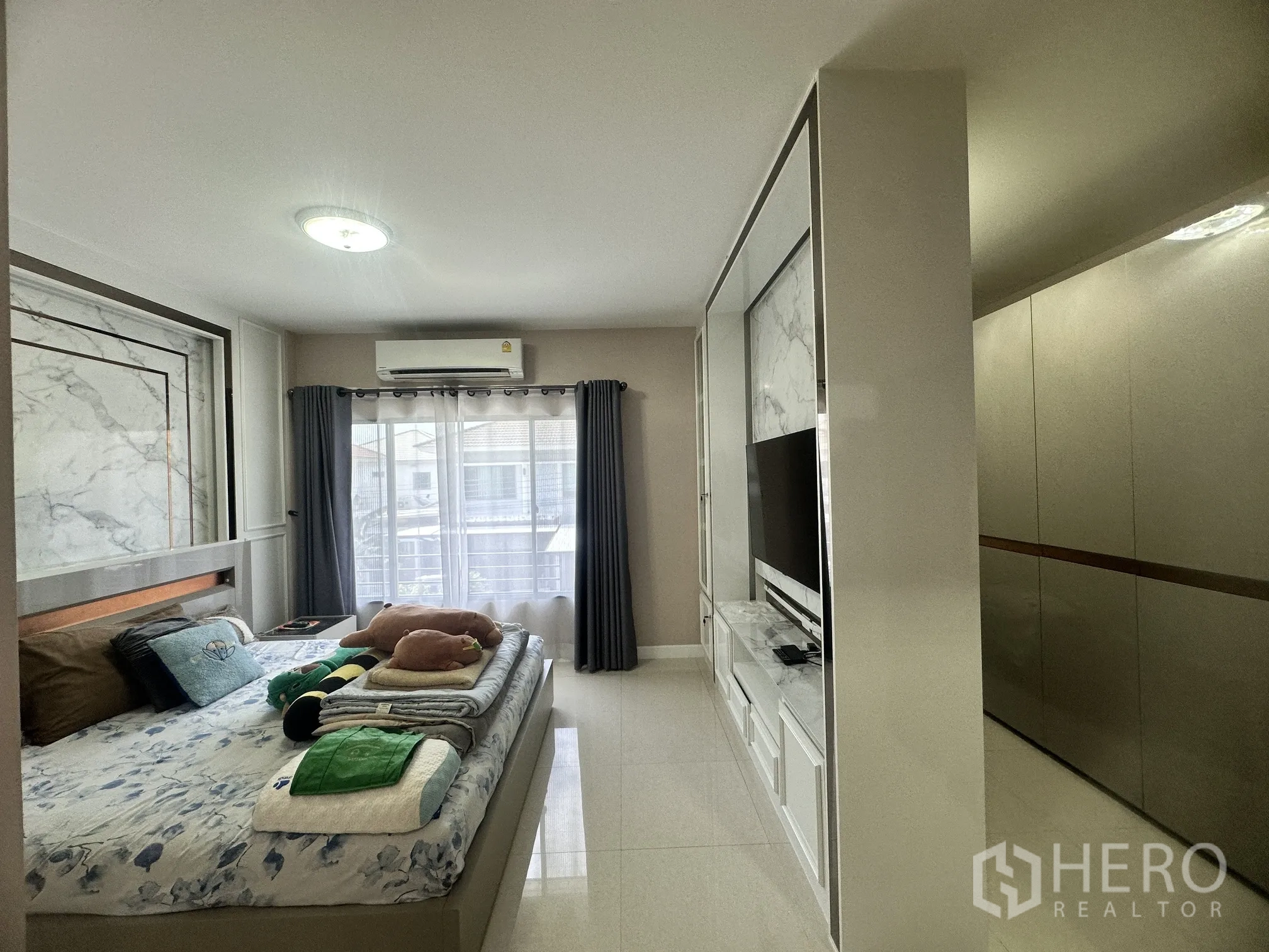 Detached House for sale in Pak Kret, Nonthaburi - Master bedroom with built-in TV wall, wardrobe, and balcony window.