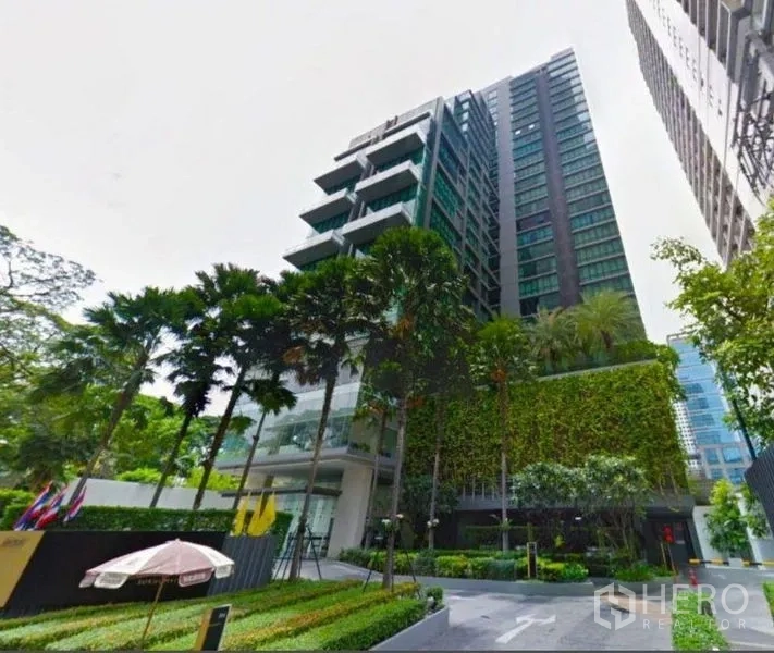 คอนโด ขายในWatthana, Bangkok - อาคารคอนโดสูงพร้อมผนังสีเขียว ระเบียง และทางเข้าเรียงรายด้วยต้นปาล์ม