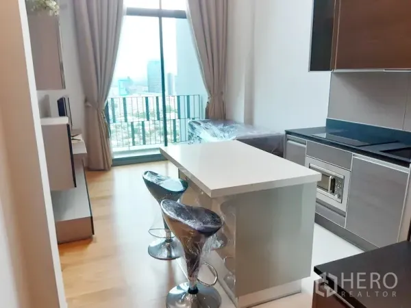 คอนโด ให้เช่าในKhlong Toei, Bangkok - พื้นที่นั่งเล่นคอนโดสว่างพร้อมเคาน์เตอร์ครัวไอแลนด์และหน้าต่างสูงจรดเพดานมองเห็นวิวเมืองกรุงเทพฯ ย่านคลองเตย