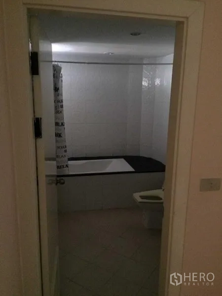 คอนโด ให้เช่าในWatthana, Bangkok - ห้องน้ำกระเบื้องสีขาว พร้อมอ่างอาบน้ำ ผ้าม่านกั้นอาบน้ำ และโถสุขภัณฑ์