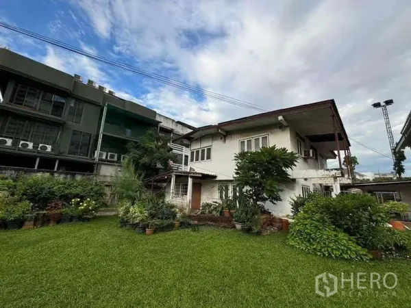 บ้าน ให้เช่าในSuan Luang, Bangkok - บ้านเดี่ยวสองชั้น พร้อมสนามหญ้ากว้าง ต้นไม้ใหญ่ และกระถางต้นไม้ ท่ามกลางย่านเมืองใต้ท้องฟ้ามีเมฆ